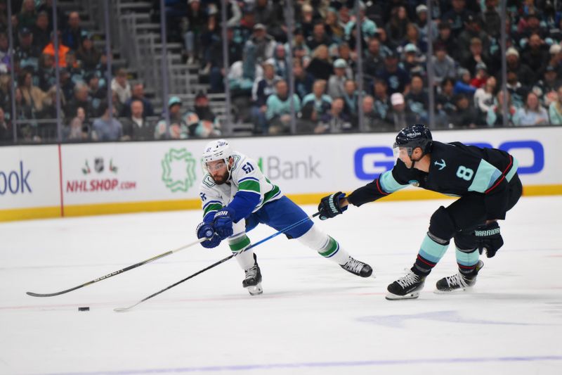 Nov 24, 2023; Seattle, Washington, USA; Vancouver Canucks defenseman Mark Friedman (51) and Seattle Kraken defenseman Brian Dumoulin (8) reach for the puck during the first period at Climate Pledge Arena. Mandatory Credit: Steven Bisig-USA TODAY Sports