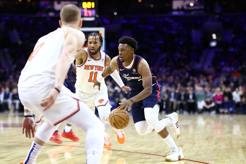 PHILADELPHIA, PENNSYLVANIA - FEBRUARY 22: Kyle Lowry #7 of the Philadelphia 76ers dribbles between Donte DiVincenzo #0 and Jalen Brunson #11 of the New York Knicks during the first quarter at the Wells Fargo Center on February 22, 2024 in Philadelphia, Pennsylvania. (Photo by Tim Nwachukwu/Getty Images)