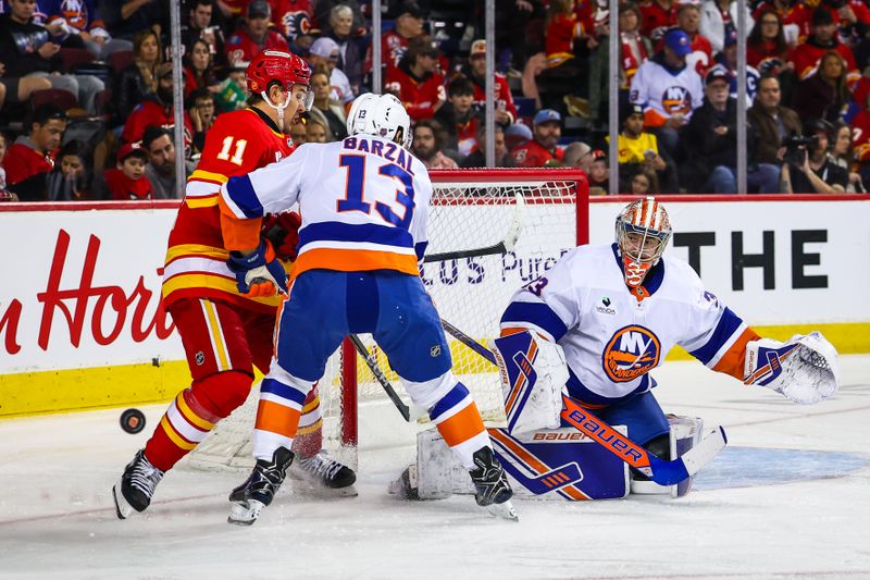 Jan 17, 2026; Calgary, Alberta, CAN; New York Islanders center Mathew Barzal (13) and Calgary Flames center Mikael Backlund (11) battle for the puck in front of New York Islanders goaltender David Rittich (33) during the second period at Scotiabank Saddledome. Mandatory Credit: Sergei Belski-Imagn Images