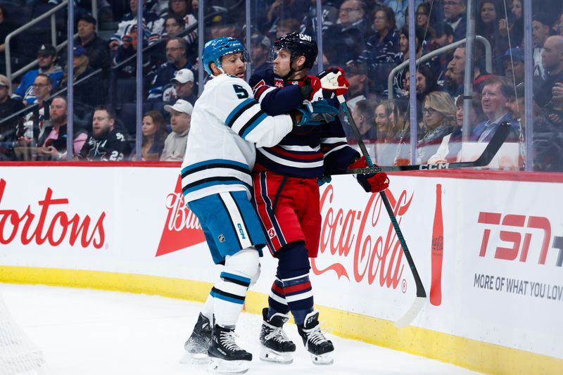 Oct 18, 2024; Winnipeg, Manitoba, CAN;  San Jose Sharks defenseman Matt Benning (5) ties up Winnipeg Jets forward Nikolaj Ehlers (27) during the second period at Canada Life Centre. Mandatory Credit: Terrence Lee-Imagn Images