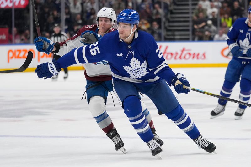 Mar 19, 2025; Toronto, Ontario, CAN; Toronto Maple Leafs defenceman Brandon Carlo (25) tries to slow up Colorado Avalanche forward Brock Nelson (11) during the first period at Scotiabank Arena. Mandatory Credit: John E. Sokolowski-Imagn Images