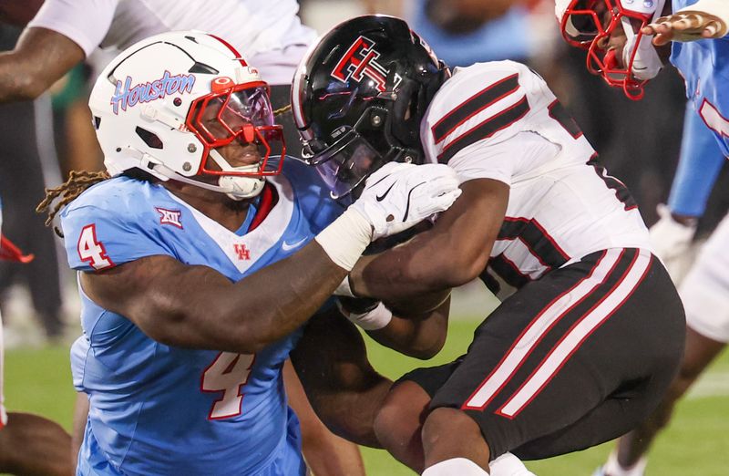 Oct 4, 2025; Houston, Texas, USA; Texas Tech Red Raiders running back J'Koby Williams (20) is tackled by Houston Cougars defensive end Brandon Mack (4) in the second half at TDECU Stadium. Mandatory Credit: Thomas Shea-Imagn Images