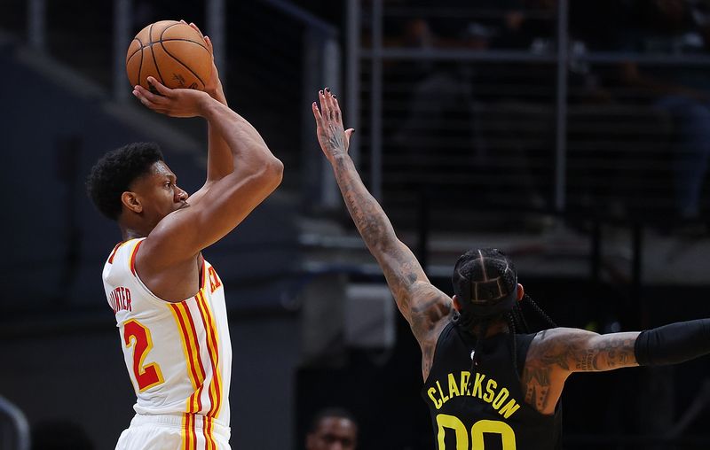 ATLANTA, GEORGIA - FEBRUARY 27:  De'Andre Hunter #12 of the Atlanta Hawks shoots a three-point basket against Jordan Clarkson #00 of the Utah Jazz during the fourth quarter at State Farm Arena on February 27, 2024 in Atlanta, Georgia.  NOTE TO USER: User expressly acknowledges and agrees that, by downloading and/or using this photograph, user is consenting to the terms and conditions of the Getty Images License Agreement.  (Photo by Kevin C. Cox/Getty Images)