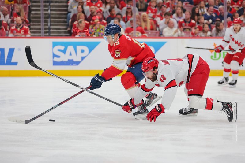 May 24, 2025; Sunrise, Florida, USA; Florida Panthers center Anton Lundell (15) and Carolina Hurricanes left wing Jordan Martinook (48) goes for the puck during the first period in game three of the Eastern Conference Final of the 2025 Stanley Cup Playoffs at Amerant Bank Arena. Mandatory Credit: Sam Navarro-Imagn Images