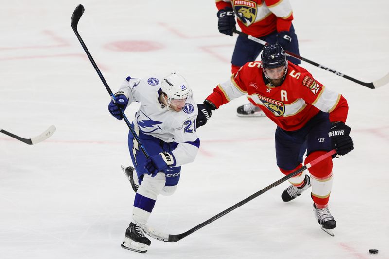 Apr 23, 2024; Sunrise, Florida, USA; Tampa Bay Lightning center Brayden Point (21) and Florida Panthers defenseman Aaron Ekblad (5) battle for the puck during the third period in game two of the first round of the 2024 Stanley Cup Playoffs at Amerant Bank Arena. Mandatory Credit: Sam Navarro-USA TODAY Sports