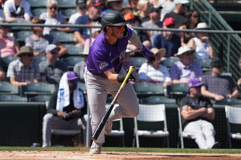 Mar 10, 2025; Tempe, Arizona, USA; Colorado Rockies catcher Hunter Goodman (15) hits a single against the Los Angeles Angels in the second inning at Tempe Diablo Stadium. Mandatory Credit: Rick Scuteri-Imagn Images