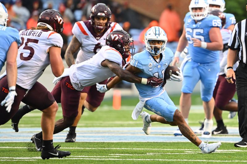 Oct 1, 2022; Chapel Hill, North Carolina, USA; North Carolina Tar Heels wide receiver Josh Downs (11) is tackled by Virginia Tech Hokies defensive back Chamarri Conner (1) in the third quarter at Kenan Memorial Stadium. Mandatory Credit: Bob Donnan-USA TODAY Sports