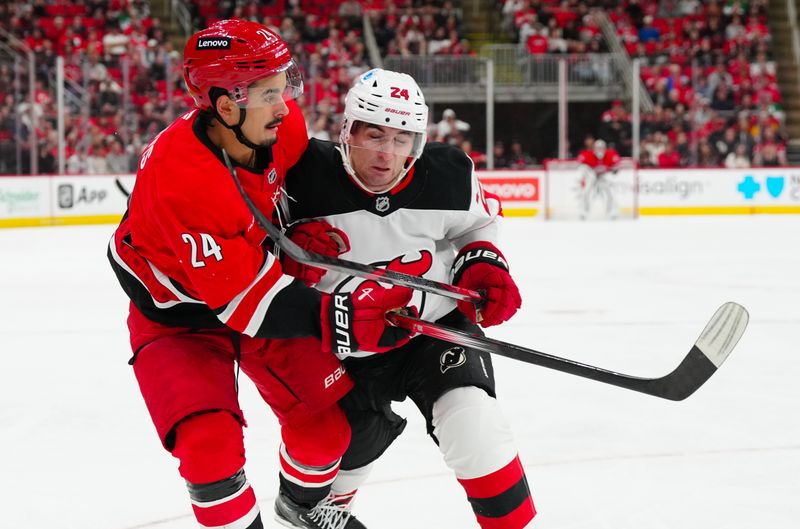 Oct 15, 2024; Raleigh, North Carolina, USA;  Carolina Hurricanes center Seth Jarvis (24) gets the shot away against New Jersey Devils defenseman Seamus Casey (24) during the second period at PNC Arena. Mandatory Credit: James Guillory-Imagn Images