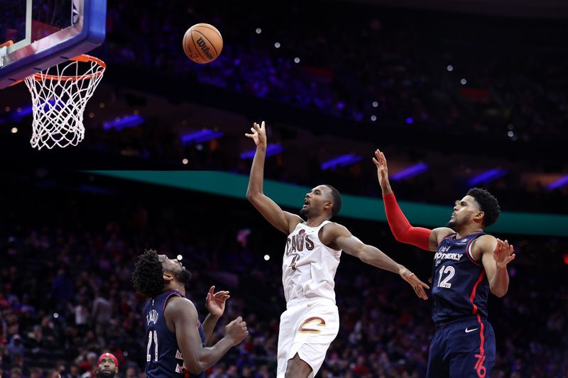 PHILADELPHIA, PENNSYLVANIA - NOVEMBER 21: Evan Mobley #4 of the Cleveland Cavaliers shoots between Joel Embiid #21 and Tobias Harris #12 of the Philadelphia 76ers during overtime at the Wells Fargo Center on November 21, 2023 in Philadelphia, Pennsylvania. NOTE TO USER: User expressly acknowledges and agrees that, by downloading and or using this photograph, User is consenting to the terms and conditions of the Getty Images License Agreement. (Photo by Tim Nwachukwu/Getty Images)