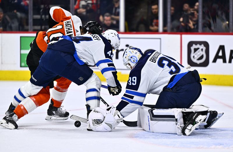 Feb 8, 2024; Philadelphia, Pennsylvania, USA; Winnipeg Jets goalie Laurent Brossoit (39) reaches to cover the puck against Philadelphia Flyers right wing Garnet Hathaway (19) with Winnipeg Jets defenseman Josh Morrissey (44) in the first period at Wells Fargo Center. Mandatory Credit: Kyle Ross-USA TODAY Sports