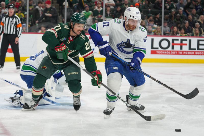 Feb 19, 2024; Saint Paul, Minnesota, USA; Minnesota Wild right wing Brandon Duhaime (21) and Vancouver Canucks defenseman Ian Cole (82) fight for possession in front of the Vancouver Canucks net in the second period at Xcel Energy Center. Mandatory Credit: Matt Blewett-USA TODAY Sports