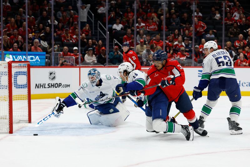Oct 19, 2025; Washington, District of Columbia, USA; Washington Capitals right wing Justin Sourdif (34) shoots the puck on Vancouver Canucks goaltender Thatcher Demko (35) as Canucks left wing Kiefer Sherwood (44) defends during the third period at Capital One Arena. Mandatory Credit: Geoff Burke-Imagn Images
