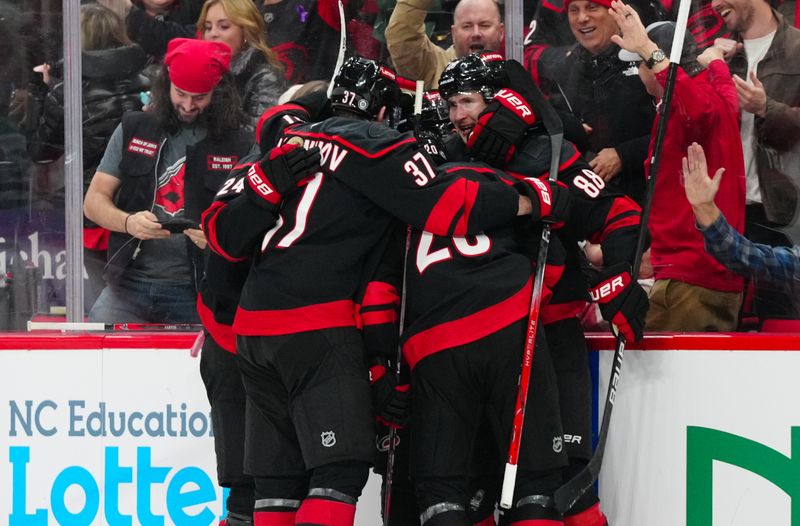 Nov 25, 2024; Raleigh, North Carolina, USA;  Carolina Hurricanes center Martin Necas (88) celebrates his goal with center Sebastian Aho (20) center Seth Jarvis (24) and  right wing Andrei Svechnikov (37) against the Dallas Stars during the third period at Lenovo Center. Mandatory Credit: James Guillory-Imagn Images