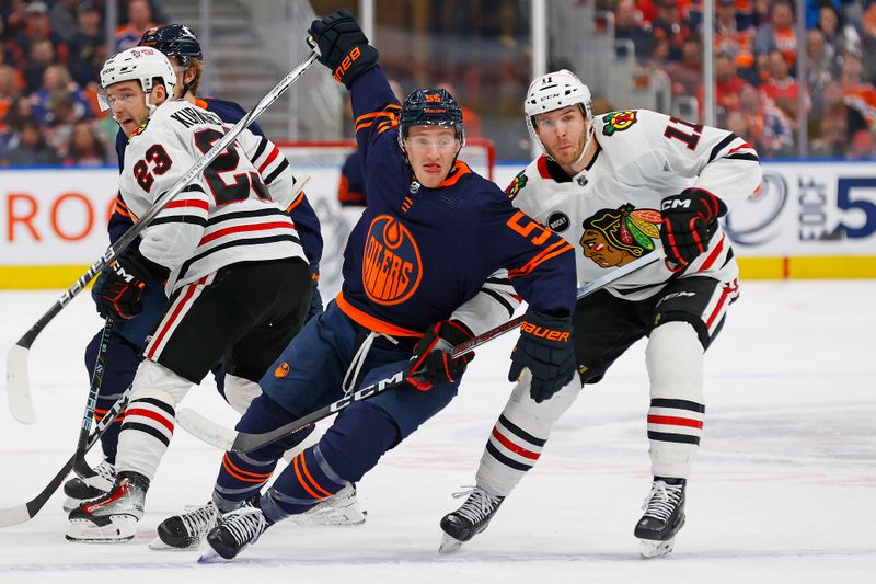 Jan 25, 2024; Edmonton, Alberta, CAN; Edmonton Oilers forward Dylan Holloway (55) and Chicago Blackhawks forward Taylor Raddysh (11) battle for position during the first period at Rogers Place. Mandatory Credit: Perry Nelson-USA TODAY Sports