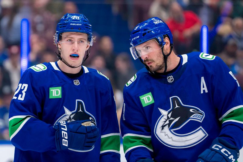 Nov 12, 2024; Vancouver, British Columbia, CAN; Vancouver Canucks forward Jonathan Lekkerimaki (23) talks with forward J.T. Miller (9) during a stop in play against the Calgary Flames in the second period at Rogers Arena. Mandatory Credit: Bob Frid-Imagn Images