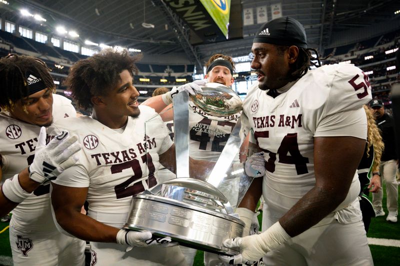 Sep 30, 2023; Arlington, Texas, USA; Texas A&M Aggies linebacker Taurean York (21) and linebacker Danny Lockhart Jr. (54) celebrate with the Southwest Classic trophy after the Aggies victory over the Arkansas Razorbacks at AT&T Stadium. Mandatory Credit: Jerome Miron-USA TODAY Sports