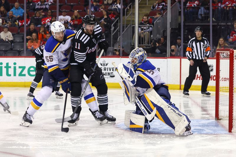 Nov 27, 2024; Newark, New Jersey, USA; St. Louis Blues goaltender Jordan Binnington (50) makes a save while defenseman Colton Parayko (55) and New Jersey Devils right wing Stefan Noesen (11) battle in front  during the second period at Prudential Center. Mandatory Credit: Ed Mulholland-Imagn Images