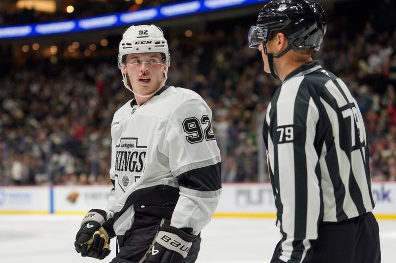 Oct 13, 2025; Saint Paul, Minnesota, USA; Los Angeles Kings defenseman Brandt Clarke (92) speaks with linesman Kiel Murchison after receiving a Minnesota Wild high stick in the second period at Grand Casino Arena. Mandatory Credit: Matt Blewett-Imagn Images