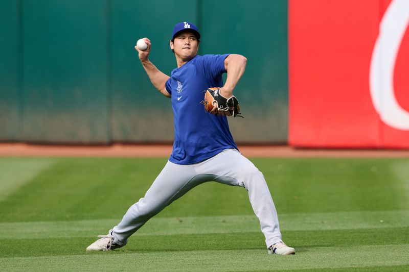 Aug 2, 2024; Oakland, California, USA; Los Angeles Dodgers designated hitter Shohei Ohtani (17) throws the ball in the outfield during warmups before the game between the Los Angeles Dodgers and the Oakland Athletics at Oakland-Alameda County Coliseum. Mandatory Credit: Robert Edwards-USA TODAY Sports