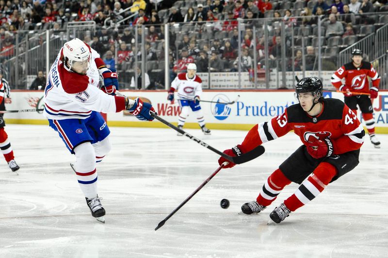 Feb 24, 2024; Newark, New Jersey, USA; Montreal Canadiens right wing Josh Anderson (17) shoots the puck while being defended by New Jersey Devils defenseman Luke Hughes (43) during the first period at Prudential Center. Mandatory Credit: John Jones-USA TODAY Sports