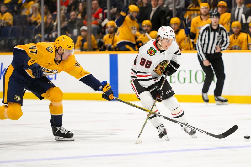 Jan 16, 2025; Nashville, Tennessee, USA;  Nashville Predators right wing Michael McCarron (47) pokes the puck from Chicago Blackhawks center Connor Bedard (98) during the second period at Bridgestone Arena. Mandatory Credit: Steve Roberts-Imagn Images