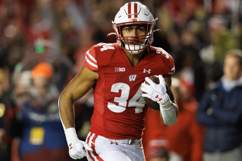 Nov 18, 2023; Madison, Wisconsin, USA;  Wisconsin Badgers running back Jackson Acker (34) rushes for a touchdown during the second quarter against the Nebraska Cornhuskers at Camp Randall Stadium. Mandatory Credit: Jeff Hanisch-USA TODAY Sports