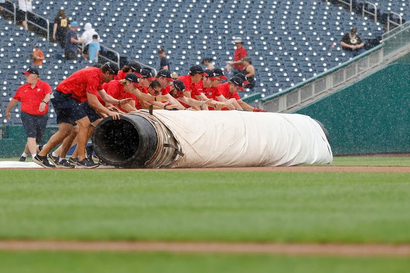 Jul 25, 2024; Washington, District of Columbia, USA; Members of the Washington Nationals grounds crew roll out the infield tarp as a rain delay is called in the first inning of the Nationals' game against the San Diego Padres at Nationals Park. Mandatory Credit: Geoff Burke-USA TODAY Sports