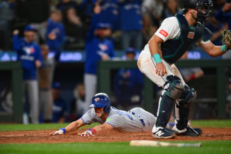 May 10, 2025; Seattle, Washington, USA; Toronto Blue Jays second baseman Ernie Clement (22) scores a run past Seattle Mariners catcher Cal Raleigh (29) during the eighth inning at T-Mobile Park. Mandatory Credit: Steven Bisig-Imagn Images