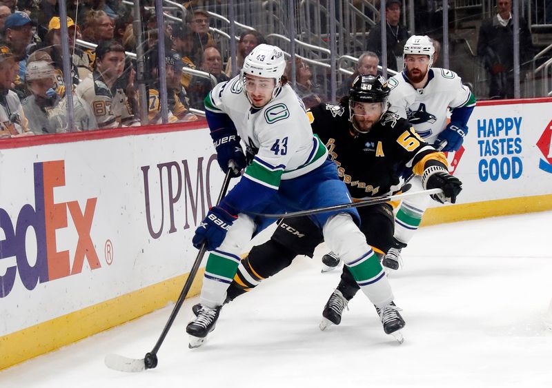 Jan 11, 2024; Pittsburgh, Pennsylvania, USA; Vancouver Canucks defenseman Quinn Hughes (43) moves the puck against pressure from Pittsburgh Penguins defenseman Kris Letang (58) during the third period at PPG Paints Arena. The Canucks won 4-3 in overtime. Mandatory Credit: Charles LeClaire-USA TODAY Sports