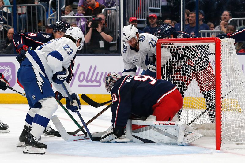 Nov 21, 2024; Columbus, Ohio, USA; Columbus Blue Jackets goalie Elvis Merzlikins (90) covers a loose puck as Tampa Bay Lightning center Mikey Eyssimont (23) looks for a rebound during the first period at Nationwide Arena. Mandatory Credit: Russell LaBounty-Imagn Images