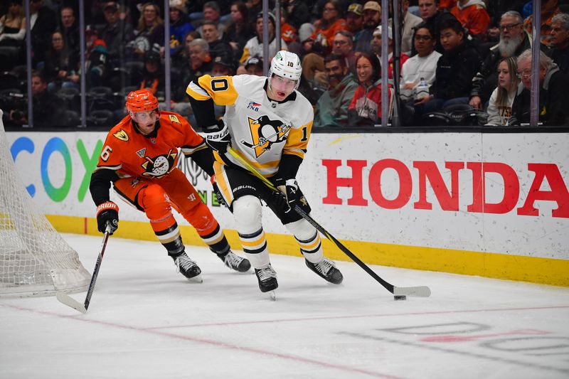 Jan 23, 2025; Anaheim, California, USA; Pittsburgh Penguins left wing Drew O'Connor (10) moves the puck ahead of Anaheim Ducks defenseman Brian Dumoulin (6) during the second period at Honda Center. Mandatory Credit: Gary A. Vasquez-Imagn Images