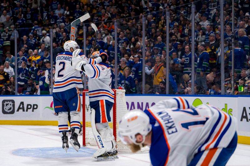 May 20, 2024; Vancouver, British Columbia, CAN;  As Edmonton Oilers defenseman Mattias Ekholm (14) picks up the game puck defenseman Evan Bouchard (2) and goalie Stuart Skinner (74) celebrate their victory over the Vancouver Canucks in game seven of the second round of the 2024 Stanley Cup Playoffs at Rogers Arena. Mandatory Credit: Bob Frid-USA TODAY Sports