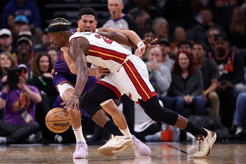 PHOENIX, ARIZONA - NOVEMBER 06: Jimmy Butler #22 of the Miami Heat drives against Devin Booker #1 of the Phoenix Suns during the second half at Footprint Center on November 06, 2024 in Phoenix, Arizona. NOTE TO USER: User expressly acknowledges and agrees that, by downloading and or using this photograph, User is consenting to the terms and conditions of the Getty Images License Agreement.  (Photo by Chris Coduto/Getty Images)