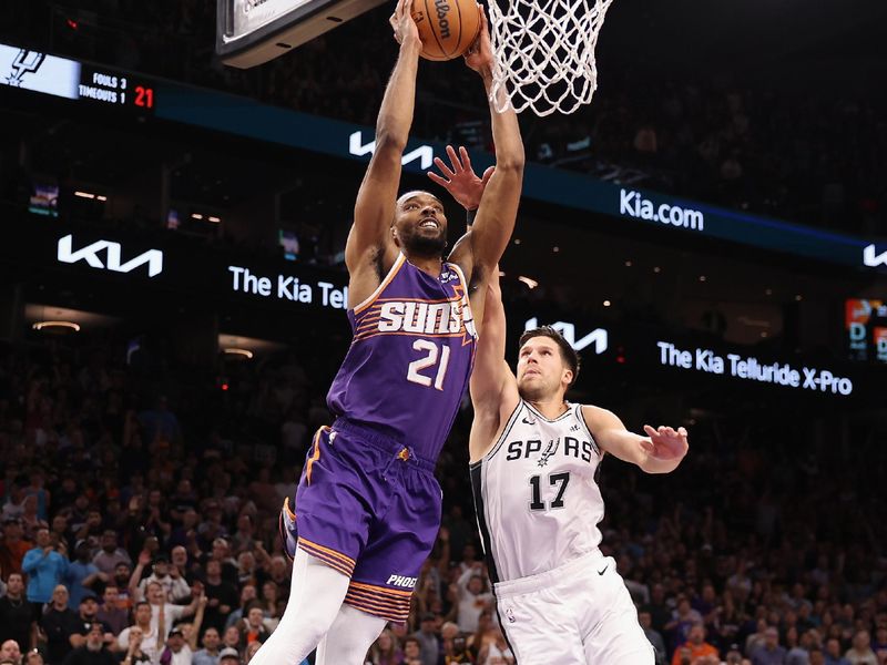 PHOENIX, ARIZONA - NOVEMBER 02: Keita Bates-Diop #21 of the Phoenix Suns slam dunks ahead of Doug McDermott #17 of the San Antonio Spurs during the second half of the NBA game at Footprint Center on November 02, 2023 in Phoenix, Arizona. The Spurs defeated the Suns 132-121.  NOTE TO USER: User expressly acknowledges and agrees that, by downloading and or using this photograph, User is consenting to the terms and conditions of the Getty Images License Agreement.  (Photo by Christian Petersen/Getty Images)