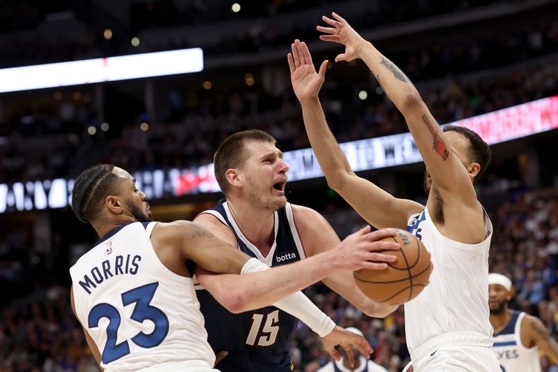 DENVER, COLORADO - APRIL 10: Nikola Jokic #15 of the Denver Nuggets is fouled going to the basket against Monte Morris #23 and Kyle Anderson #1 of the Minnesota Timberwolves during the first quarter at Ball Arena on April 10, 2024 in Denver, Colorado. NOTE TO USER: User expressly acknowledges and agrees that, by downloading and or using this photograph, User is consenting to the terms and conditions of the Getty Images License Agreement.  (Photo by Matthew Stockman/Getty Images)