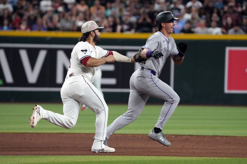 May 18, 2025; Phoenix, Arizona, USA; Arizona Diamondbacks third base Eugenio Suarez (28) tags out Colorado Rockies outfielder Jordan Beck (27) during a run down in the sixth inning at Chase Field. Mandatory Credit: Rick Scuteri-Imagn Images
