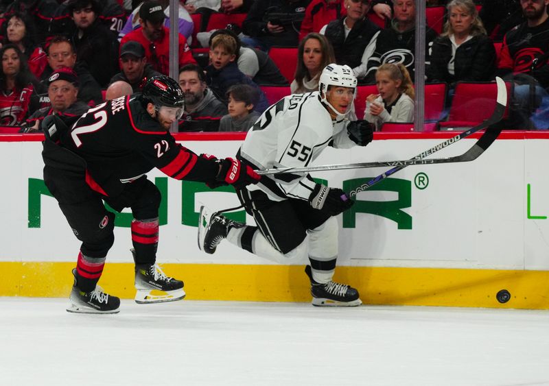 Jan 15, 2024; Raleigh, North Carolina, USA; Los Angeles Kings right wing Quinton Byfield (55) and Carolina Hurricanes defenseman Brett Pesce (22) skate after the puck during the second period at PNC Arena. Mandatory Credit: James Guillory-USA TODAY Sports