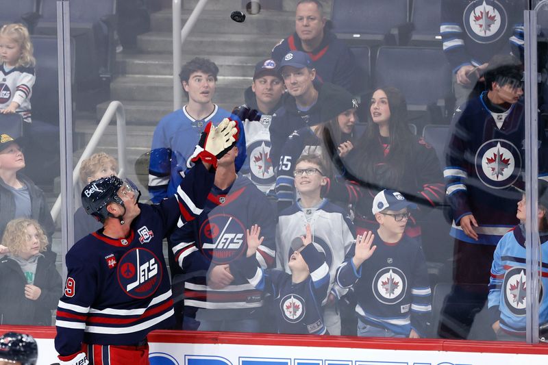 Oct 23, 2025; Winnipeg, Manitoba, CAN; Winnipeg Jets center Jonathan Toews (19) tosses puck to a fan before a game against the Seattle Kraken at Canada Life Centre. Mandatory Credit: James Carey Lauder-Imagn Images