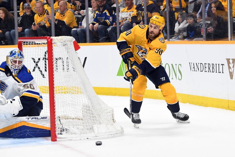 Apr 4, 2024; Nashville, Tennessee, USA; Nashville Predators center Ryan O'Reilly (90) passes the puck from behind they net during the first period against the St. Louis Blues at Bridgestone Arena. Mandatory Credit: Christopher Hanewinckel-USA TODAY Sports