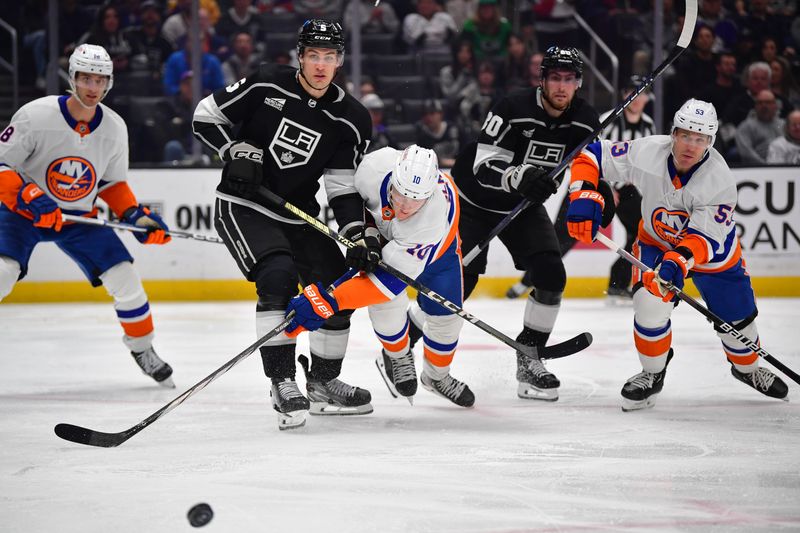 Mar 11, 2024; Los Angeles, California, USA; Los Angeles Kings defenseman Andreas Englund (5) plays for the puck against New York Islanders right wing Simon Holmstrom (10) during the third period at Crypto.com Arena. Mandatory Credit: Gary A. Vasquez-USA TODAY Sports