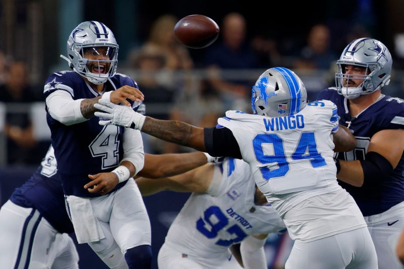 Dallas Cowboys quarterback Dak Prescott (4) throws a pass under pressure from Detroit Lions defensive tackle Mekhi Wingo (94) in the first half of an NFL football game in Arlington, Texas, Sunday, Oct. 13, 2024. (AP Photo/Gareth Patterson)