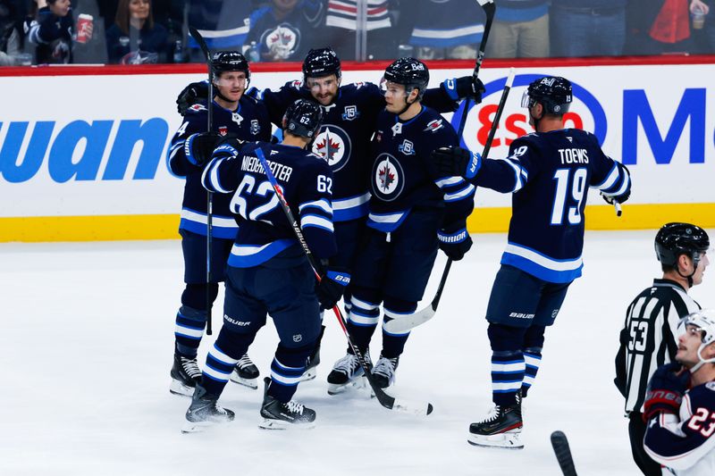 Nov 18, 2025; Winnipeg, Manitoba, CAN;  Winnipeg Jets defenseman Neal Pionk (4) is congratulated by his team mates on his goal against the Columbus Blue Jackets during the second period at Canada Life Centre. Mandatory Credit: Terrence Lee-Imagn Images