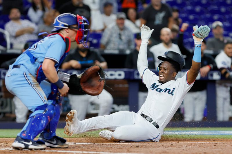 Jun 21, 2023; Miami, Florida, USA; Miami Marlins right fielder Jesus Sanchez (7) slides at home plate and scores after a two-run double from first baseman Garrett Cooper (not pictured) against the Toronto Blue Jays during the fourth inning at loanDepot Park. Mandatory Credit: Sam Navarro-USA TODAY Sports