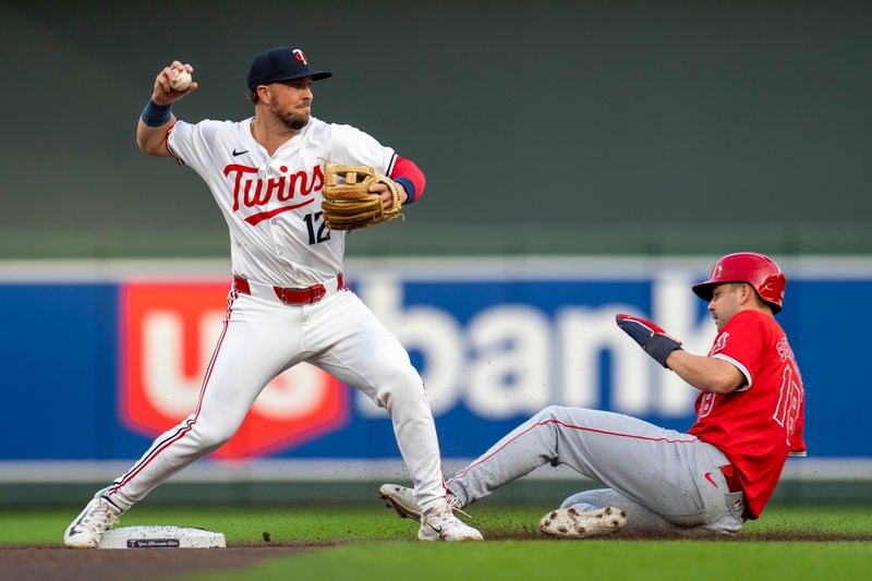 Sep 9, 2024; Minneapolis, Minnesota, USA; Minnesota Twins second baseman Kyle Farmer (12) forces out Los Angeles Angels first baseman Nolan Schanuel (18) at second base and turns a double play in the first inning at Target Field. Mandatory Credit: Jesse Johnson-Imagn Images