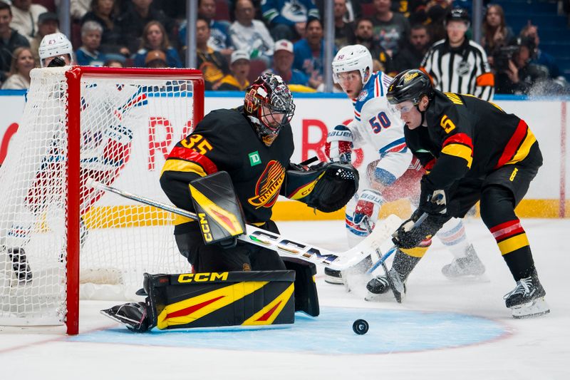 Oct 28, 2025; Vancouver, British Columbia, CAN; Vancouver Canucks defenseman Tom Willander (5) watches goalie Thatcher Demko (35) make a save against the New York Rangers in the third period at Rogers Arena. Mandatory Credit: Bob Frid-Imagn Images