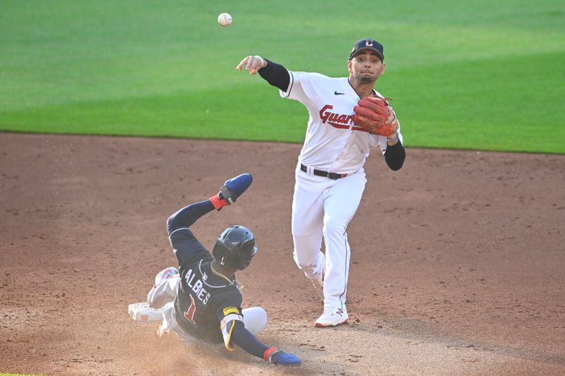 Jul 4, 2023; Cleveland, Ohio, USA; Cleveland Guardians second baseman Andres Gimenez (0) turns a double play beside Atlanta Braves second baseman Ozzie Albies (1) in the third inning at Progressive Field. Mandatory Credit: David Richard-USA TODAY Sports