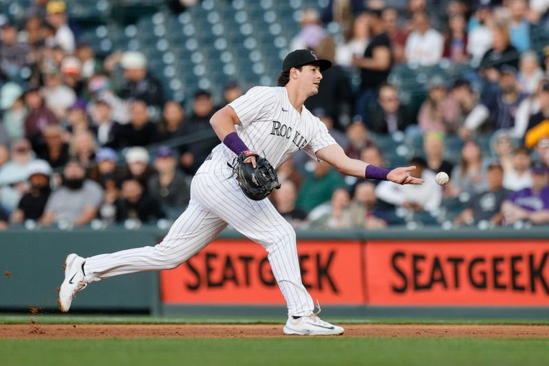 Apr 9, 2025; Denver, Colorado, USA; Colorado Rockies first baseman Michael Toglia (4) tosses the ball back to first for an out in the second inning against the Milwaukee Brewers at Coors Field. Mandatory Credit: Isaiah J. Downing-Imagn Images