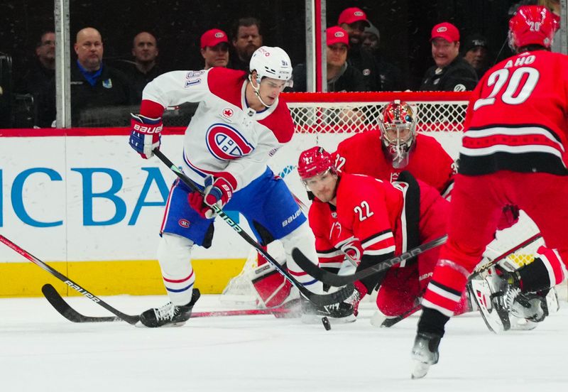 Dec 28, 2023; Raleigh, North Carolina, USA; Montreal Canadiens center Sean Monahan (91) battles for the puck against Carolina Hurricanes defenseman Brett Pesce (22) during the first period at PNC Arena. Mandatory Credit: James Guillory-USA TODAY Sports