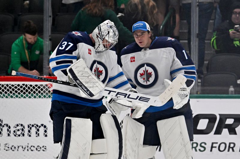 Apr 10, 2025; Dallas, Texas, USA; Winnipeg Jets goaltender Connor Hellebuyck (37) and goaltender Eric Comrie (1) celebrate on the ice after Hellebuyck gets the shutout win over the Dallas Stars at the American Airlines Center. Mandatory Credit: Jerome Miron-Imagn Images