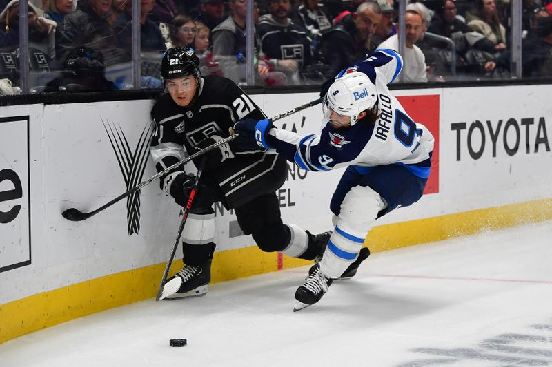 Dec 13, 2023; Los Angeles, California, USA; Winnipeg Jets left wing Alex Iafallo (9) plays for the puck against Los Angeles Kings defenseman Jordan Spence (21) during the first period at Crypto.com Arena. Mandatory Credit: Gary A. Vasquez-USA TODAY Sports